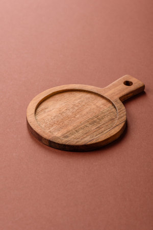 Empty wooden cutting board on a monochrome brown background.