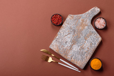 Empty wooden cutting board on a monochrome brown background. Empty board with cutlery on a dining...