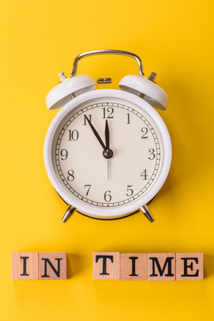 Vintage alarm clock with time or on time inscription on yellow background as a conceptual background for your inscriptionの写真素材