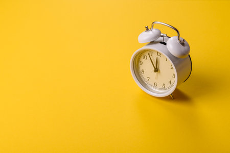 Vintage alarm clock on yellow surface as a conceptual background for deadlines for tasks in office and businessの写真素材