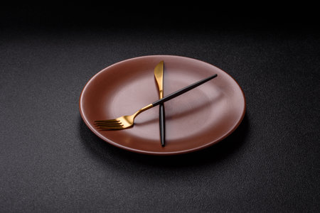 Empty plate with devices in the form of clock hands as a conceptual background for lunch time, mealの写真素材