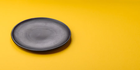 Empty round ceramic plate on yellow background.の写真素材