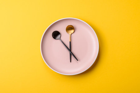 Empty plate with devices in the form of clock hands as a conceptual background for lunch time, coffee break, mealの写真素材