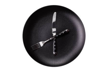 Empty plate with devices in the form of clock hands as a conceptual background for lunch time,...
