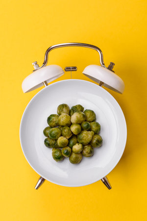 Boiled Brussels sprouts as a vegetarian side dish for lunch. Breakfast as a plate concept instead of a dial on a vintage alarm clockの写真素材