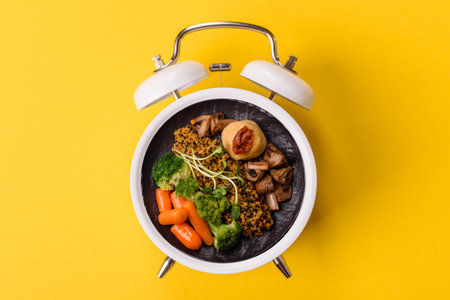 Vegetarian salad or bowls with quinoa, vegetables, and eggs on a vintage alarm clock background....