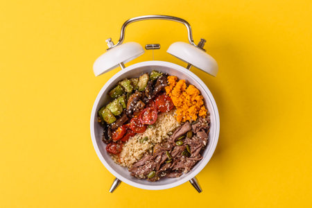 Vegetarian salad or bowls with quinoa, vegetables, and eggs on a vintage alarm clock background....