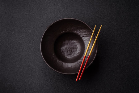 Empty round black plate for food, risotto or pasta, kitchen utensils on dining table. Empty plate on...