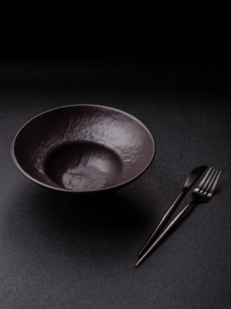 Empty round black plate for food, risotto or pasta, kitchen utensils on dining table. Empty plate on dark backgroundの写真素材