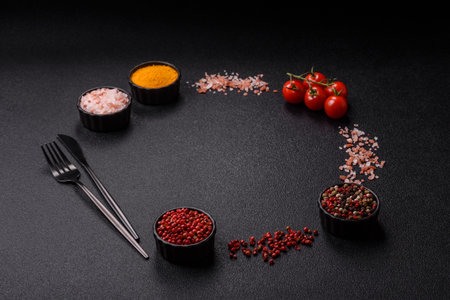 Ingredients for cooking cherry tomatoes, salt, spices and herbs on a dark concrete background