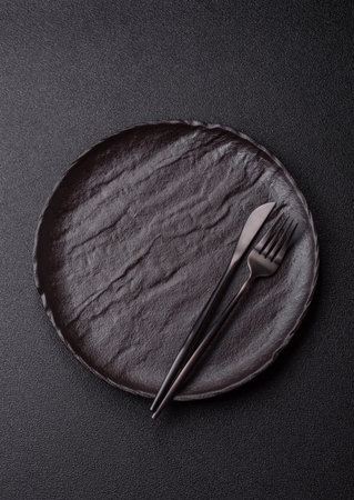 Empty round black plate for food, risotto or pasta, kitchen utensils on dining table. Empty plate on dark backgroundの写真素材