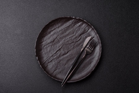Empty round black plate for food, risotto or pasta, kitchen utensils on dining table. Empty plate on dark backgroundの写真素材