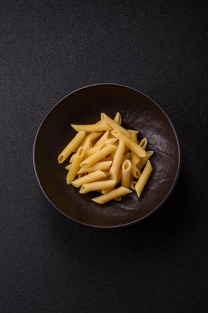 Penne pasta cooked with cheese, salt and spices. Italian food penne pasta on a dark concrete backgroundの写真素材