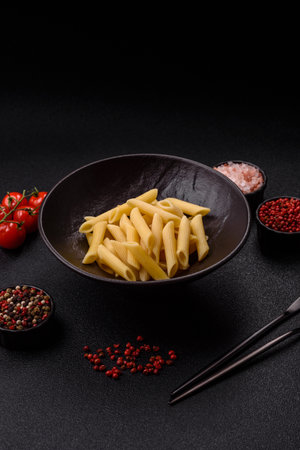 Penne pasta cooked with cheese, salt and spices. Italian food penne pasta on a dark concrete backgroundの写真素材