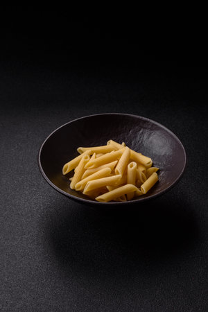 Penne pasta cooked with cheese, salt and spices. Italian food penne pasta on a dark concrete backgroundの写真素材