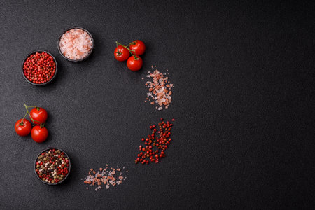 Ingredients for cooking cherry tomatoes, salt, spices and herbs on a dark concrete background