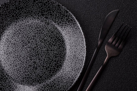 Empty round black plate for food, kitchen utensils on dining table. Empty plate on dark backgroundの写真素材