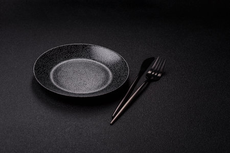 Empty round black plate for food, kitchen utensils on dining table. Empty plate on dark backgroundの写真素材