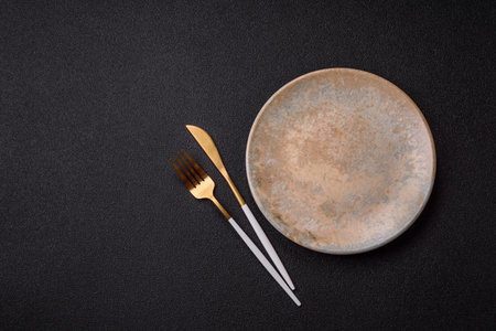 Empty round black plate for food, kitchen utensils on dining table. Empty plate on dark background