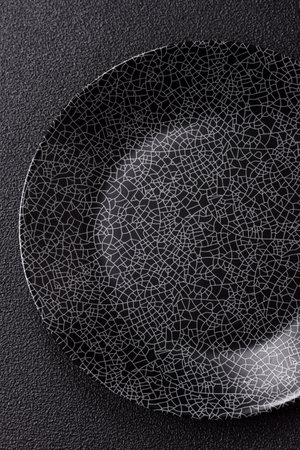 Empty round black plate for food, kitchen utensils on dining table. Empty plate on dark backgroundの写真素材