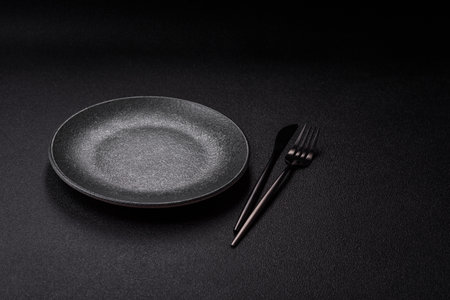 Empty round black plate for food, kitchen utensils on dining table. Empty plate on dark backgroundの写真素材