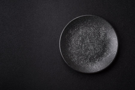Empty round black plate for food, kitchen utensils on dining table. Empty plate on dark backgroundの写真素材