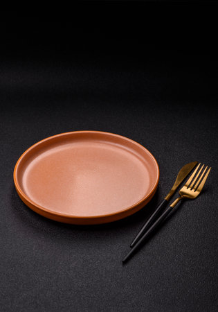 Empty round black plate for food, kitchen utensils on dining table. Empty plate on dark backgroundの写真素材