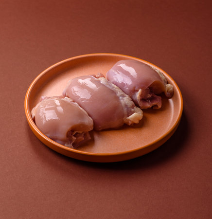 Raw chicken thigh fillet without skin and bone with salt and spices prepared for baking. Raw chicken...