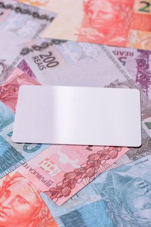 The white plastic card as a symbol of cashless payments on the background of cash paper money of...
