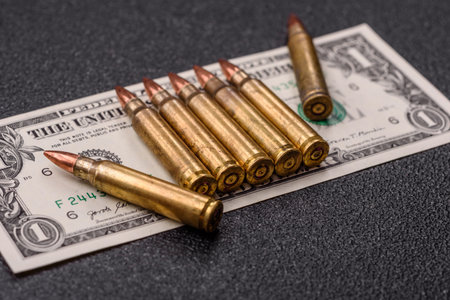 Money, cash dollars to fund weapons for war and defense against attack. Dollars for war as a conceptual backdropの写真素材