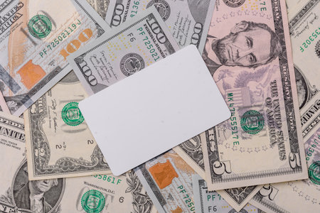 The white plastic card as a symbol of cashless payments on the background of cash paper money of...
