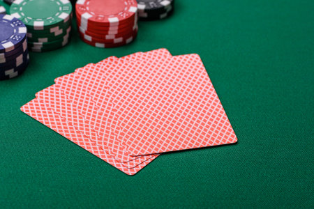Playing card game poker in casino with chips, bets and risk. Cards and chips on green felt as...