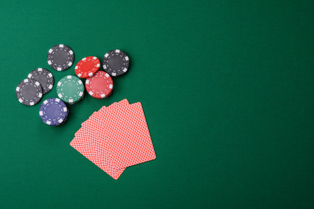 Playing card game poker in casino with chips, bets and risk. Cards and chips on green felt as...