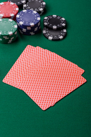 Playing card game poker in casino with chips, bets and risk. Cards and chips on green felt as...