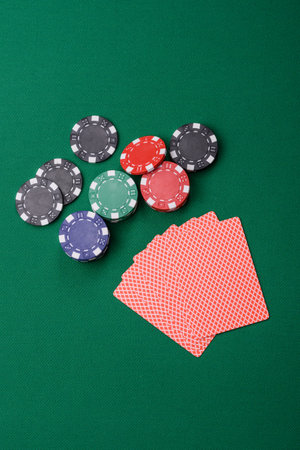 Playing card game poker in casino with chips, bets and risk. Cards and chips on green felt as...