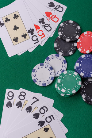 Playing card game poker in casino with chips, bets and risk. Cards and chips on green felt as...
