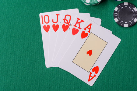 Playing card game poker in casino with chips, bets and risk. Cards and chips on green felt as...