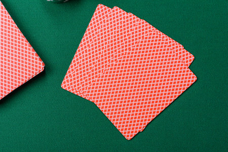 Playing card game poker in casino with chips, bets and risk. Cards and chips on green felt as...