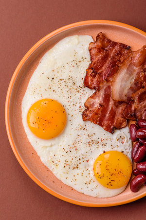 Fried egg, bacon and beans, a classic British breakfast with tomatoes and gravy. Egg, bacon and...