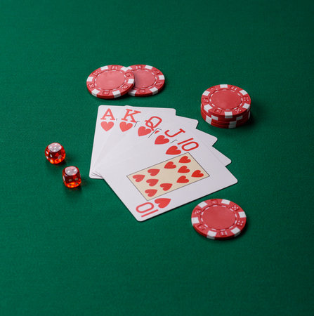 Playing card game poker in casino with chips, bets and risk. Cards and chips on green felt as...