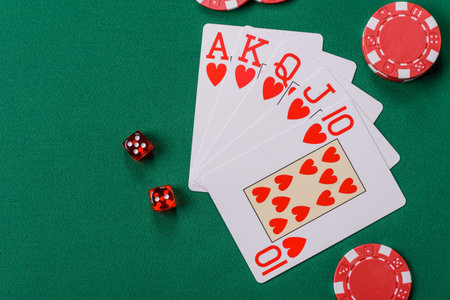 Playing card game poker in casino with chips, bets and risk. Cards and chips on green felt as...
