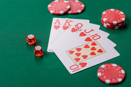 Playing card game poker in casino with chips, bets and risk. Cards and chips on green felt as...
