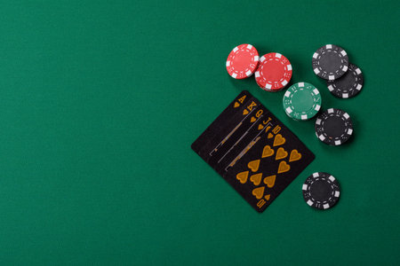 Playing card game poker in casino with chips, bets and risk. Cards and chips on green felt as...