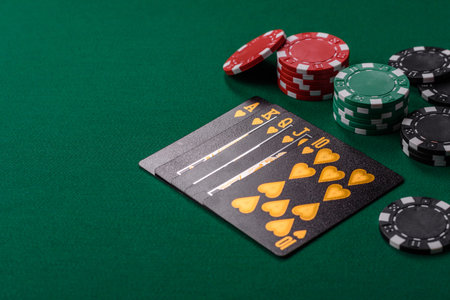 Playing card game poker in casino with chips, bets and risk. Cards and chips on green felt as...