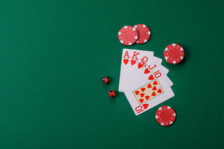 Playing card game poker in casino with chips, bets and risk. Cards and chips on green felt as...