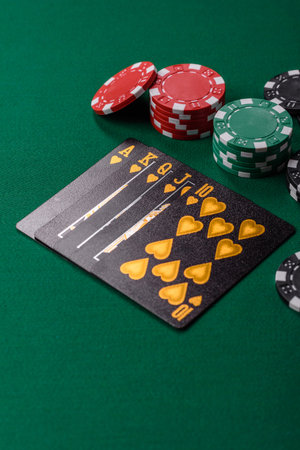 Playing card game poker in casino with chips, bets and risk. Cards and chips on green felt as...