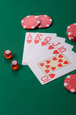 Playing card game poker in casino with chips, bets and risk. Cards and chips on green felt as...