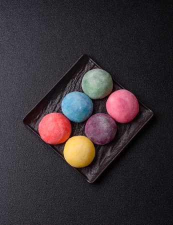 Japanese mochi, ice cream or Asian sweets made from rice flour with fruit filling. Mochi of different colors with fruit filling as food backgroundの写真素材