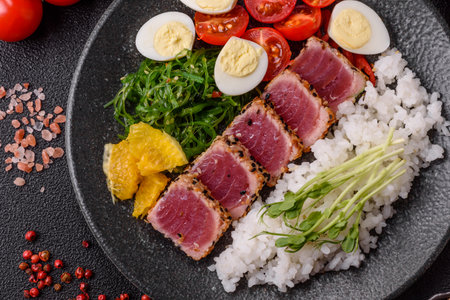 Seafood bowl, tuna tataki fillet slices with rice, oranges, tomatoes and sauce. Tuna bowl as a food background for your designの写真素材