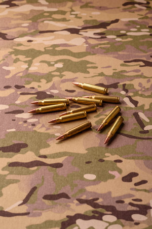 Machine gun cartridges on a camouflage background, military wallpaper. Camouflage background as a...